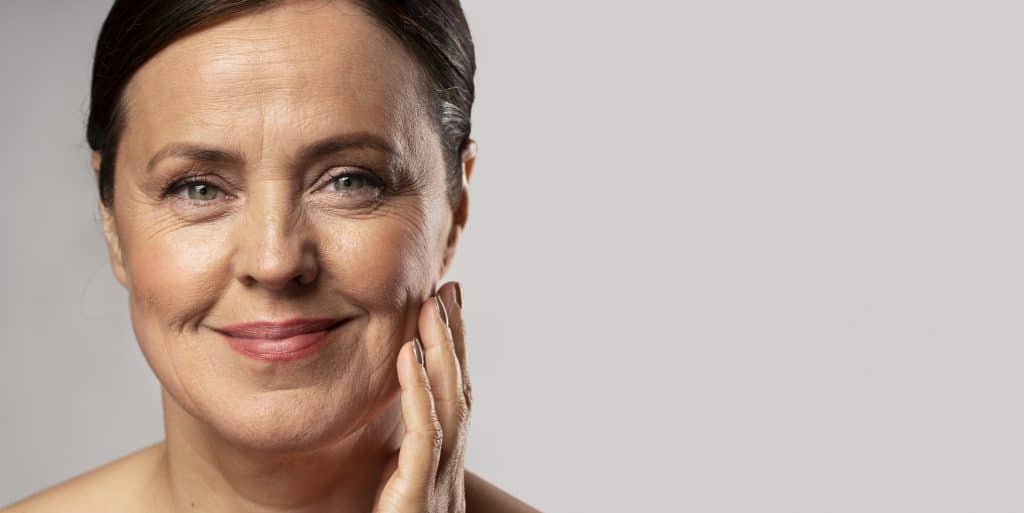 a smiling mature woman holding her hand to her face