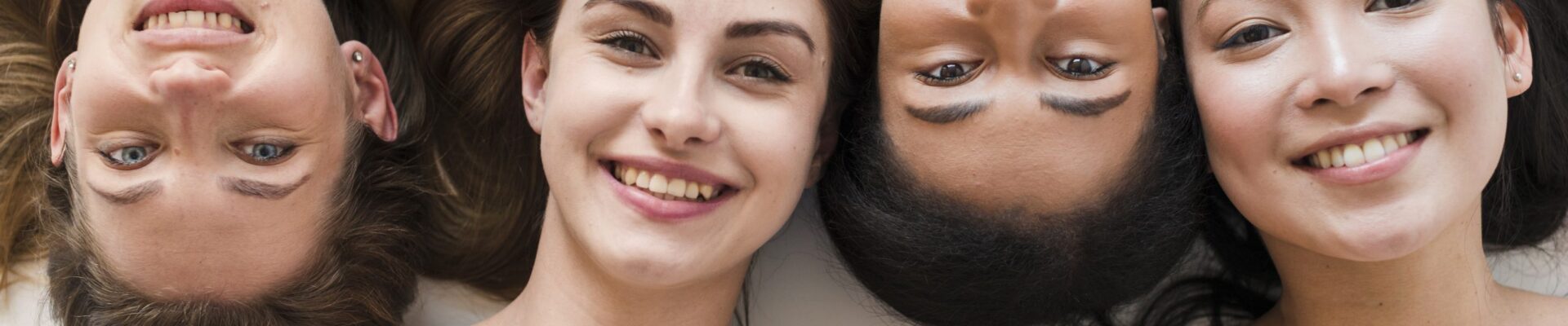Multi-racial group of young women lying on their backs smiling at the camera