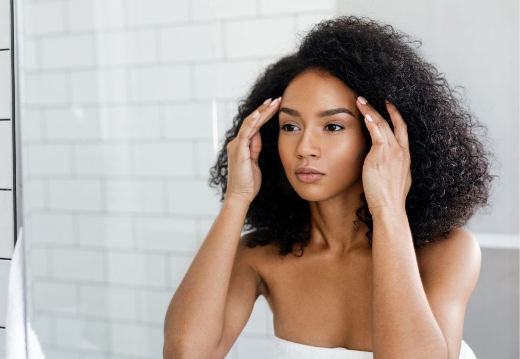 woman looking in mirror looking sad stress touching face