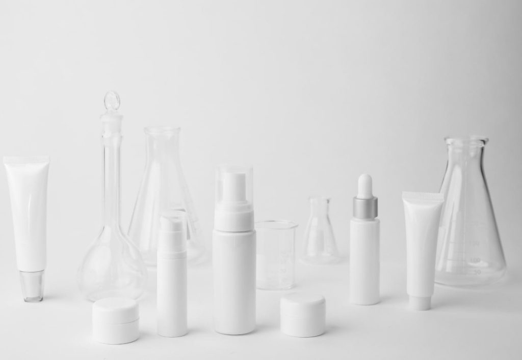 many unbranded skincare bottles on a grey studio floor background