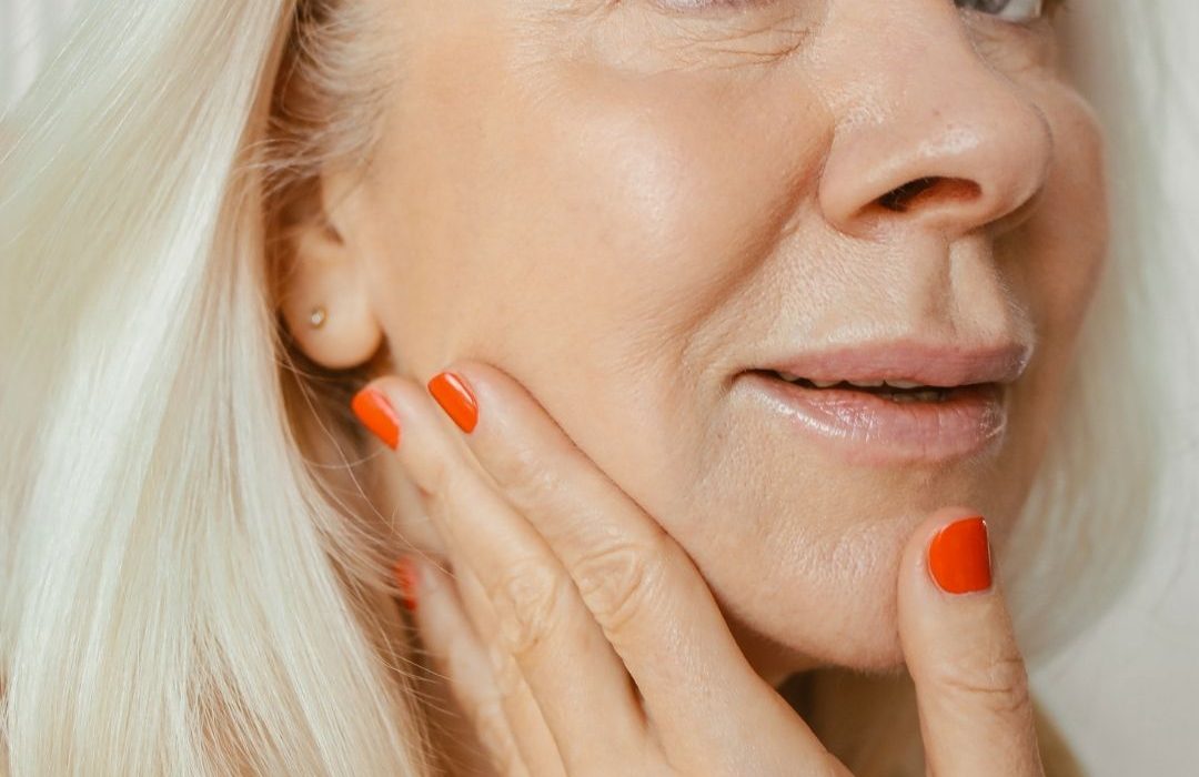 older white woman grey eyes white hair applying face serum