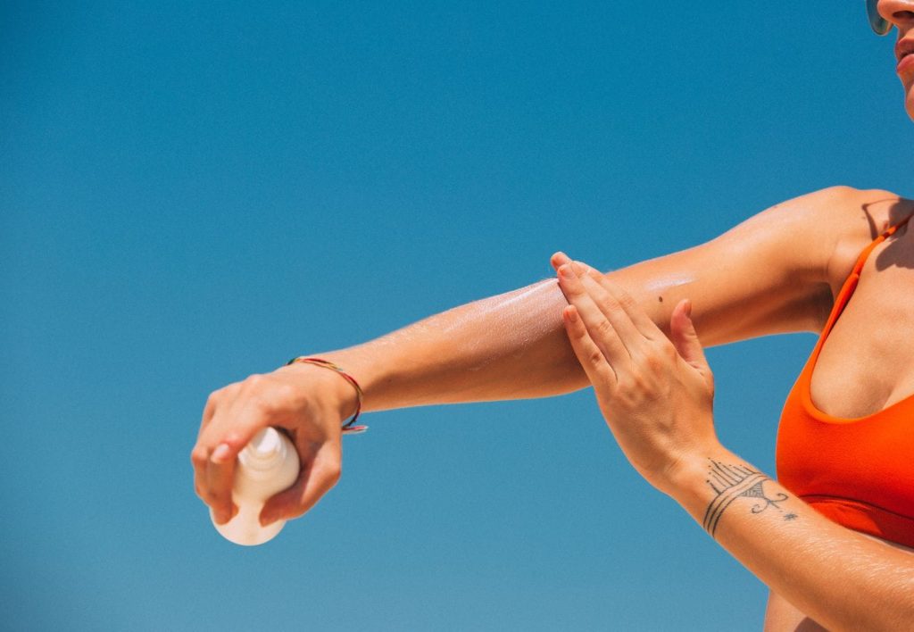 woman applying sunscreen spf and rubbing in on arm summer 