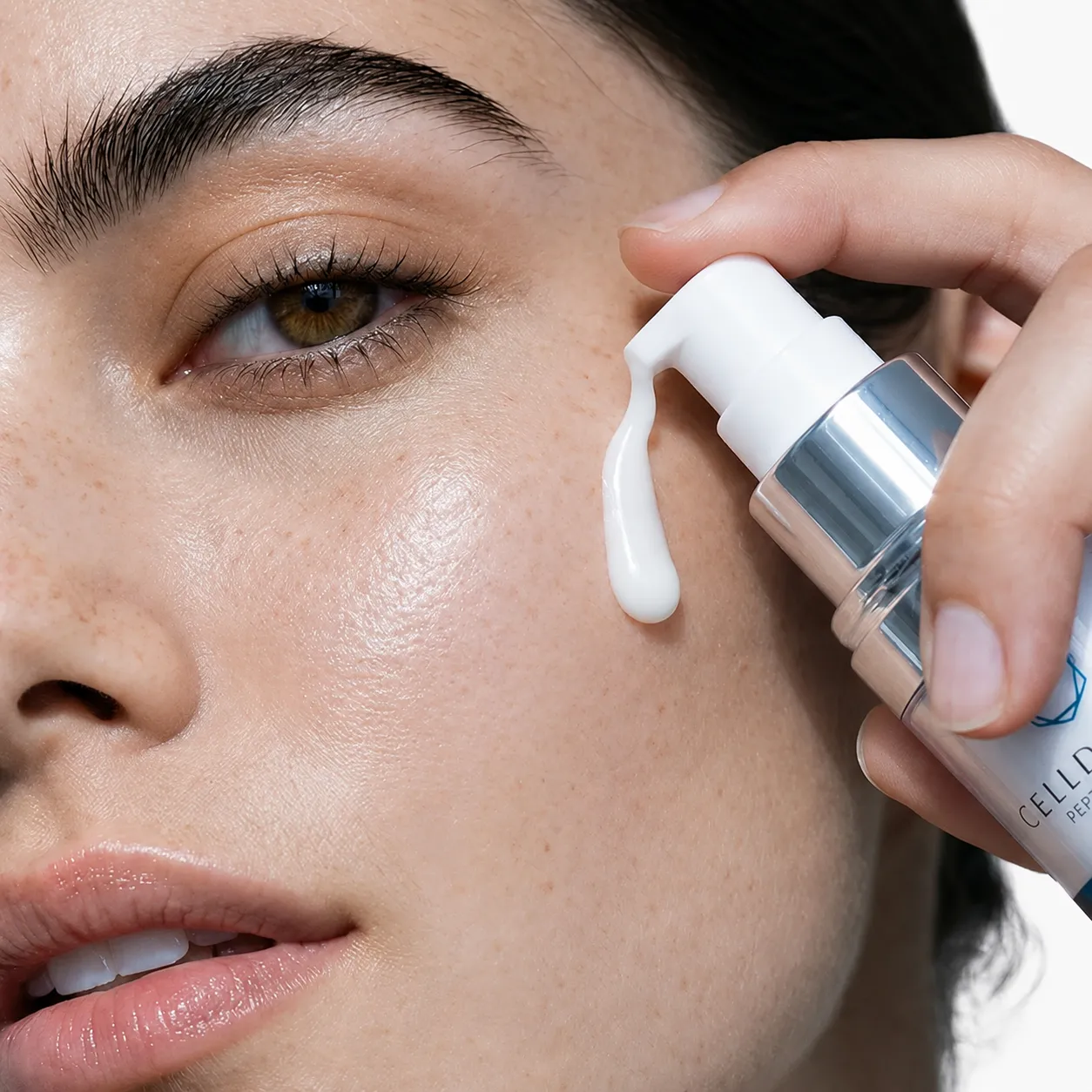 Close-up of CellDerma GF5 serum being dispensed onto glowing skin beside the eye and cheek area.