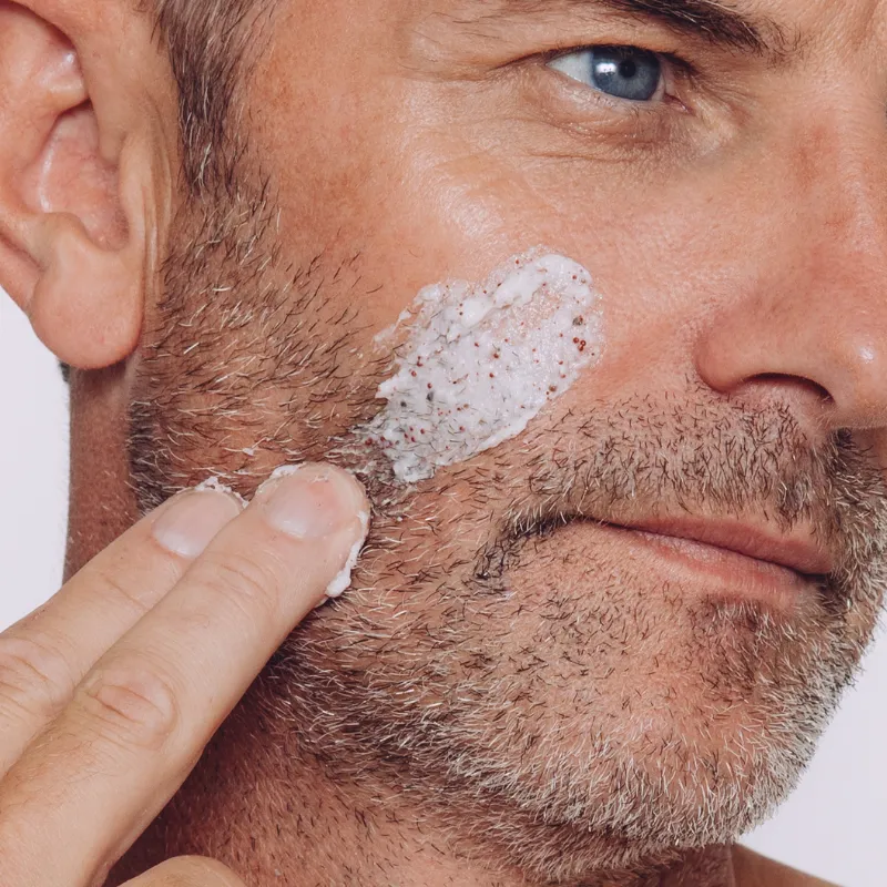 A facial exfoliating scrub being applied gently to the skin